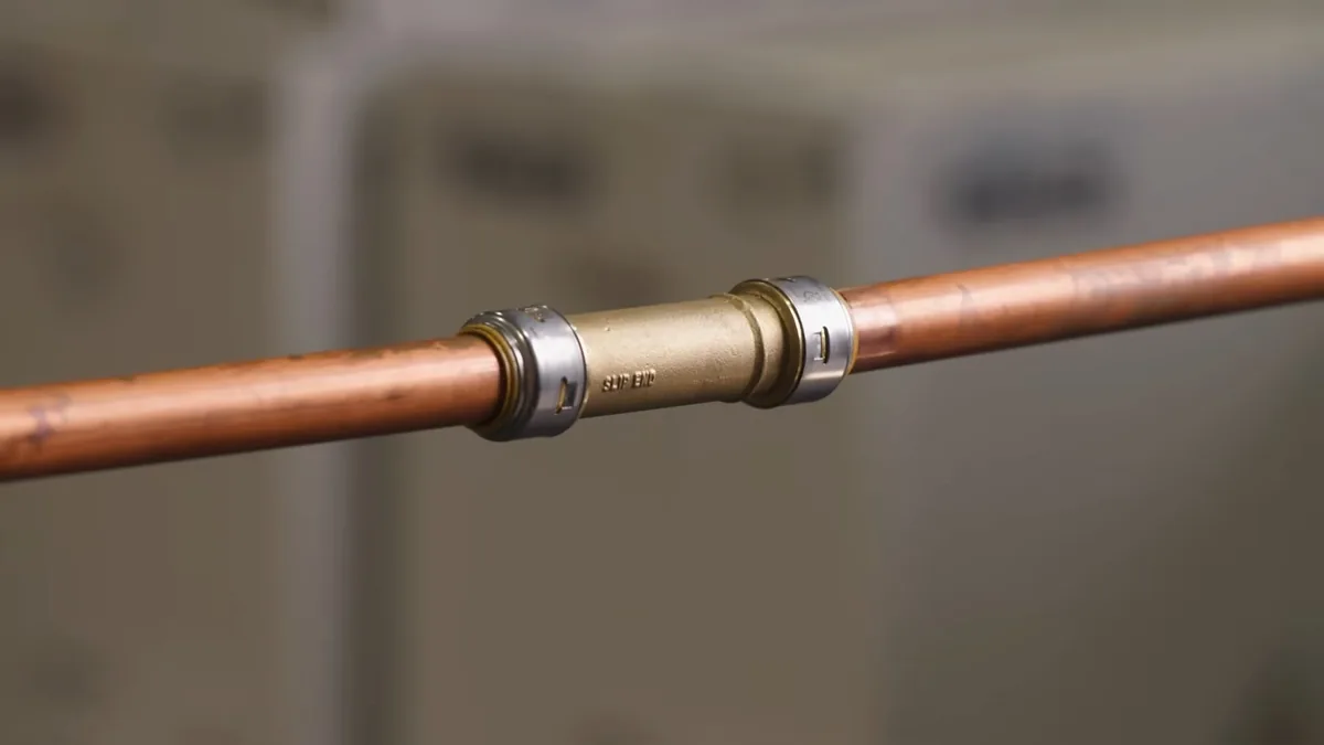 Copper pipe with a brass push-fit coupling joining two sections.